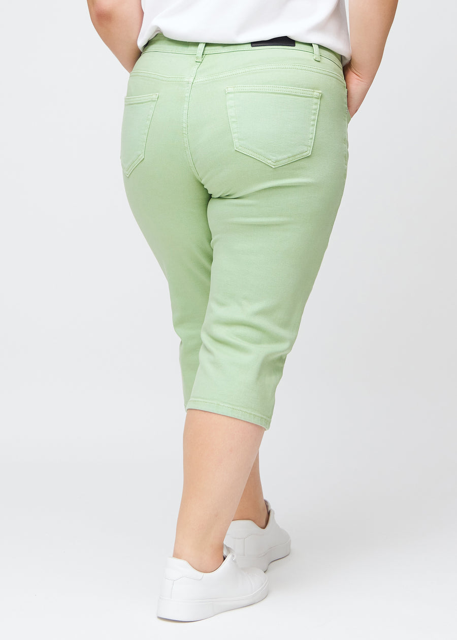Slim-capris til kvinner i pastelllysegrønt jeansstoff, fargen Mints. Sett bakfra på en plus size-modell, med fokus på passform, lengde og baklommer.