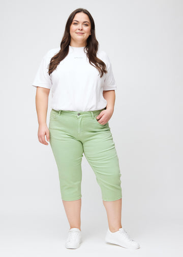 Slim-capris til kvinner i pastelllysegrønt jeansstoff, fargen Mints. Helhetsbilde av en plus size-modell med slim-capris.