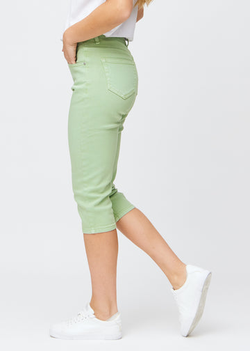 Slim-capris til kvinner i pastelllysegrønt jeansstoff, fargen Mints. Sett fra siden på en modell, med figursydd passform og mellomhøyt liv (Mid Rise).