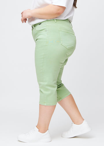 Slim-capris til kvinner i pastelllysegrønt jeansstoff, fargen Mints. Sett fra siden på en plus size-modell, med figursydd passform og mellomhøyt liv (Mid Rise).