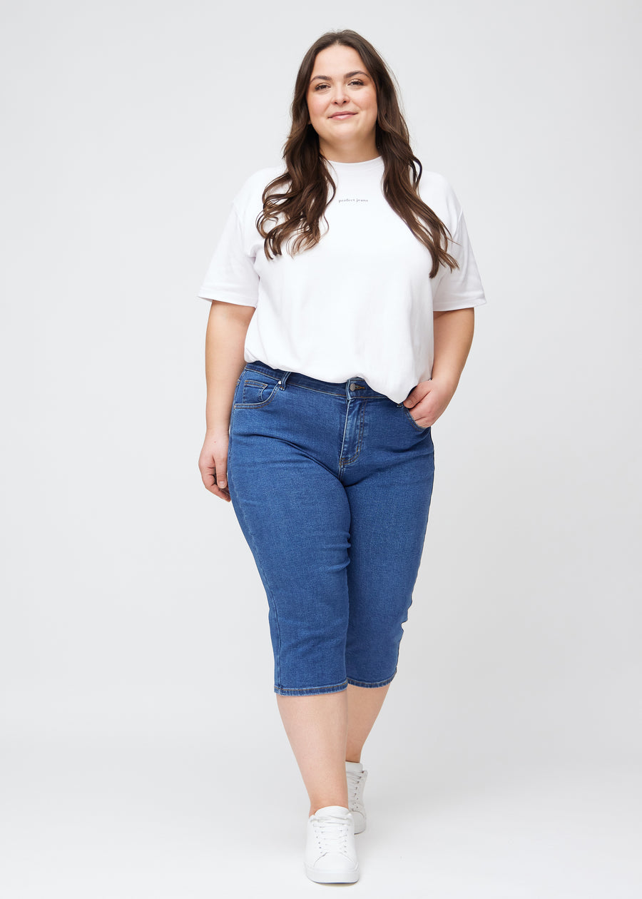 Slim-capris til kvinner i mørkeblå denim, fargen Oceans. Helhetsbilde av en plus size-modell med slim-capris.