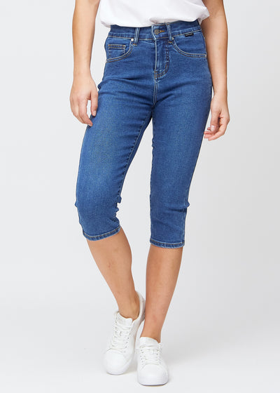 Slim-capris til kvinner i mørkeblå denim, fargen Oceans. Sett forfra på en modell, med figursydd passform til rett under kneet.