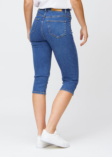 Slim-capris til kvinner i mørkeblå denim, fargen Oceans. Sett bakfra på en modell, med fokus på passform, lengde og baklommer.