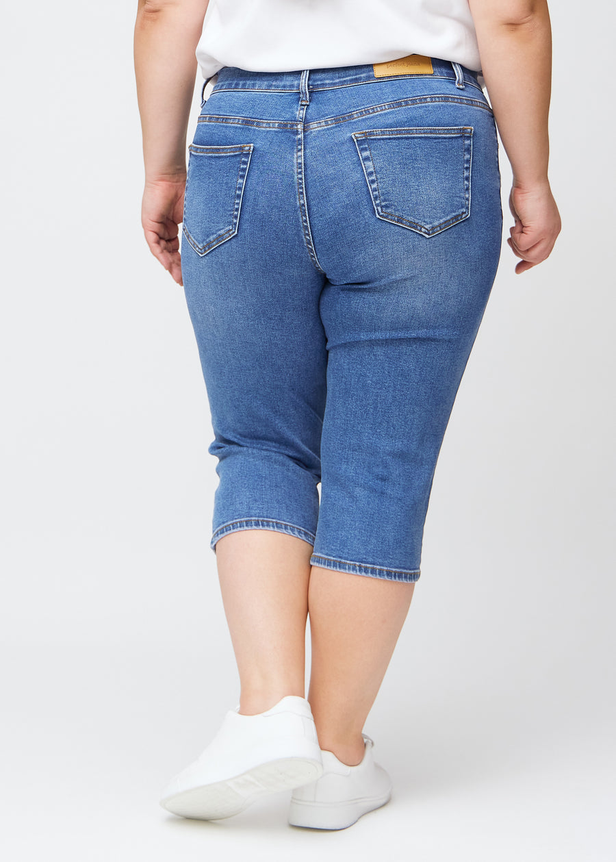 Slim-capris til kvinner i blå denim, fargen Rivers. Sett bakfra på en plus size-modell, med fokus på passform, lengde og baklommer.