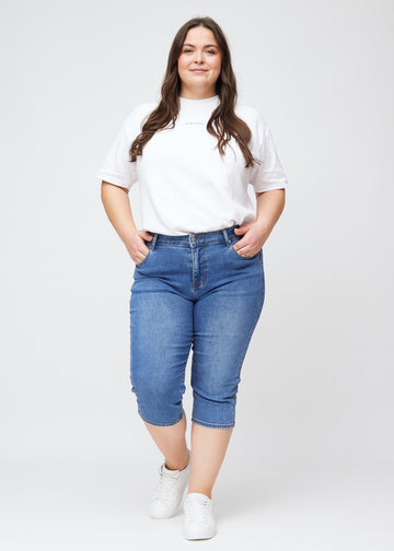 Slim-capris til kvinner i blå denim, fargen Rivers. Helhetsbilde av en plus size-modell med slim-capris.