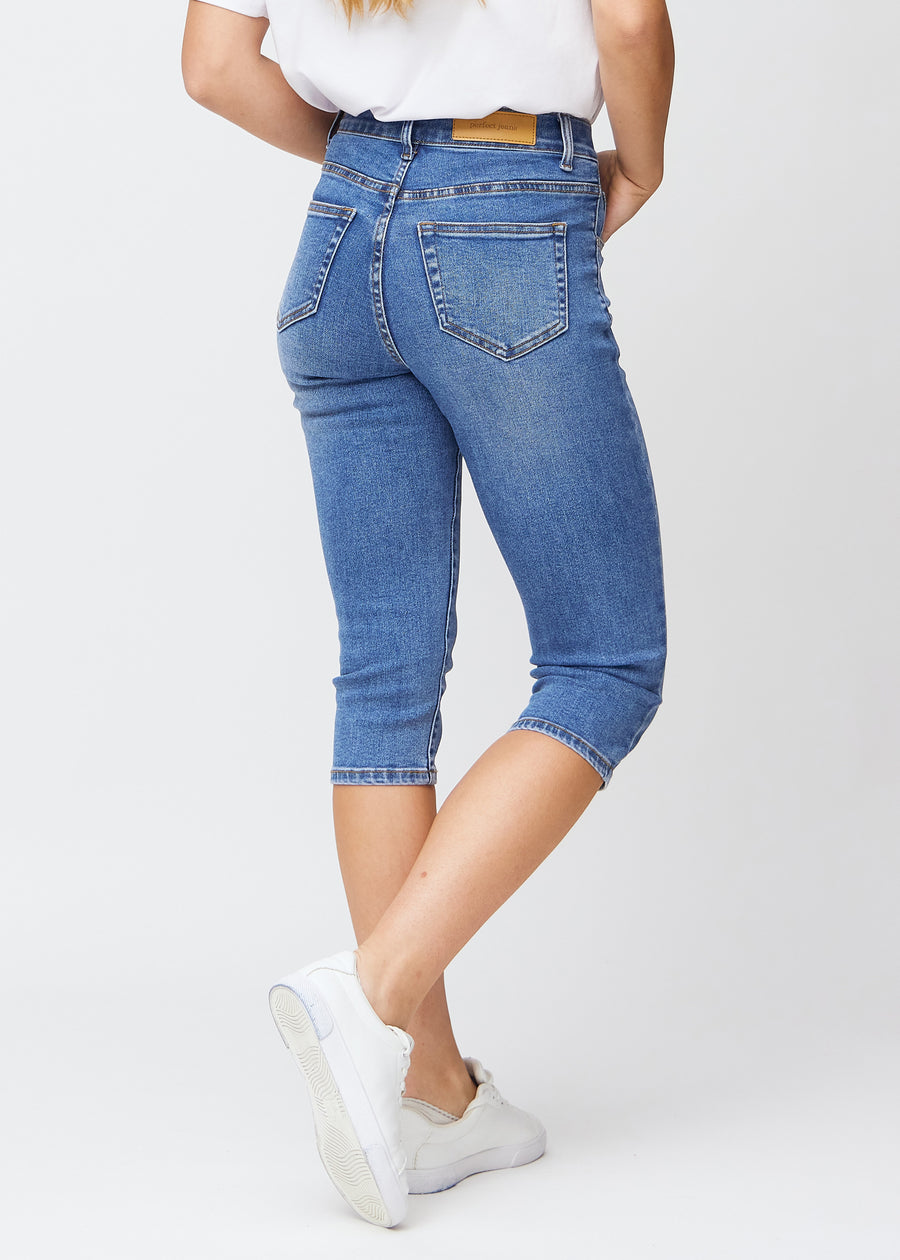 Slim-capris til kvinner i blå denim, fargen Rivers. Sett bakfra på en modell, med fokus på passform, lengde og baklommer.