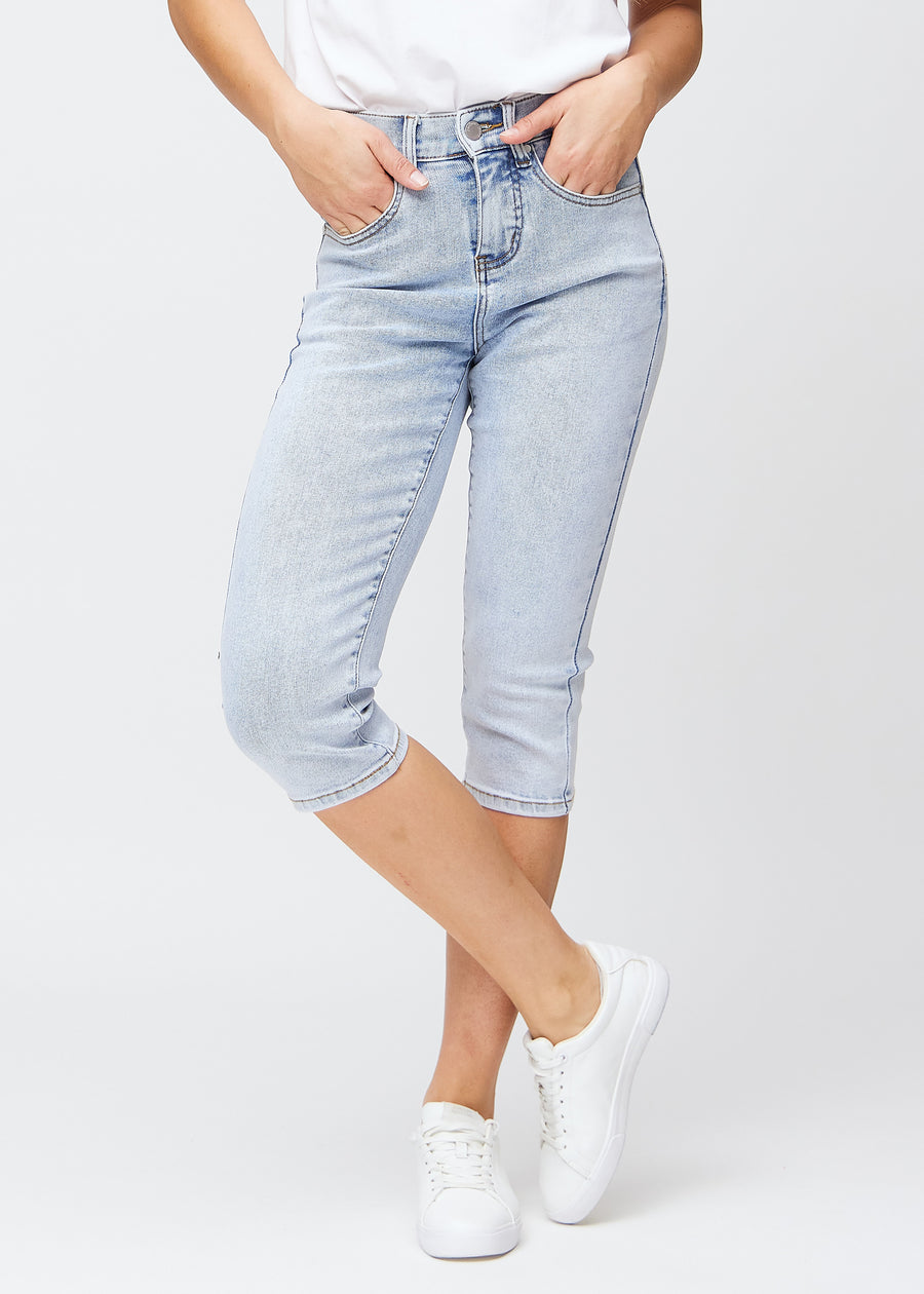 Slim-capris til kvinner i lyseblå denim, fargen Waves. Sett forfra på en modell, med figursydd passform til rett under kneet.