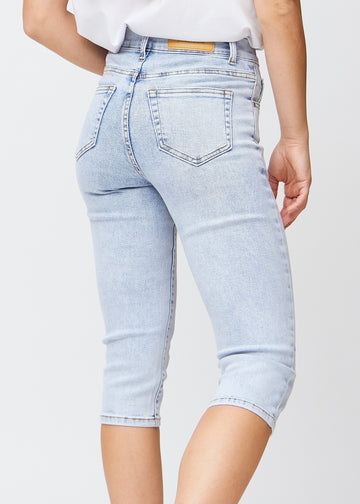 Slim-capris til kvinner i lyseblå denim, fargen Waves. Nærbilde bakfra på en modell, med fokus på baklommer og sømmer.