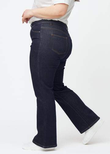 Dyp mørkeblå denim jeans til kvinner i fargen Midnights med bootcut-passform sett fra siden på plus-size-modell.