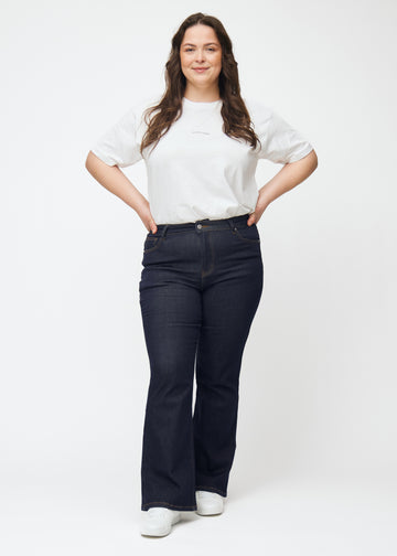 Fullt bilde av plus-size-modell i dyp mørkeblå denim jeans til kvinner i fargen Midnights med bootcut-passform.