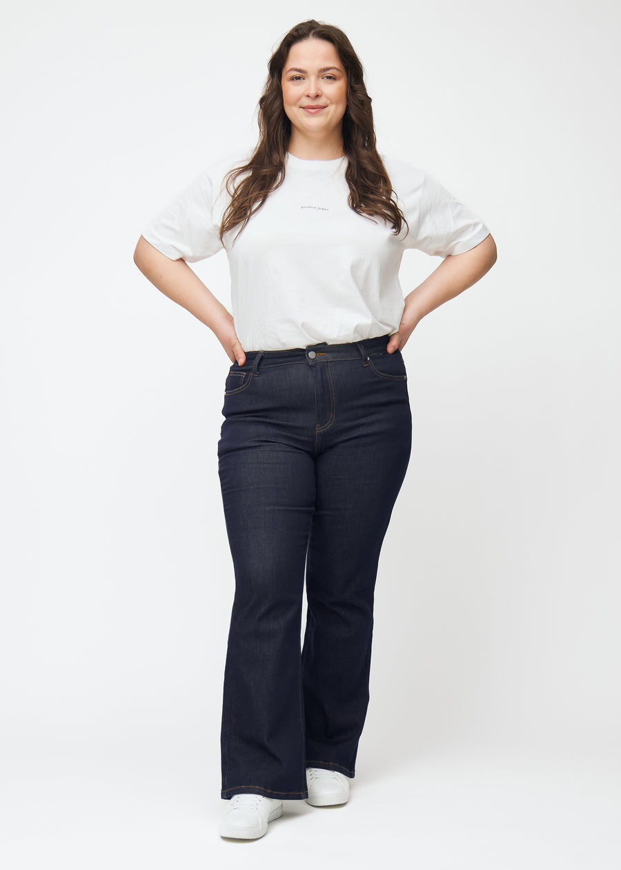Fullt bilde av plus-size-modell i dyp mørkeblå denim jeans til kvinner i fargen Midnights med bootcut-passform.