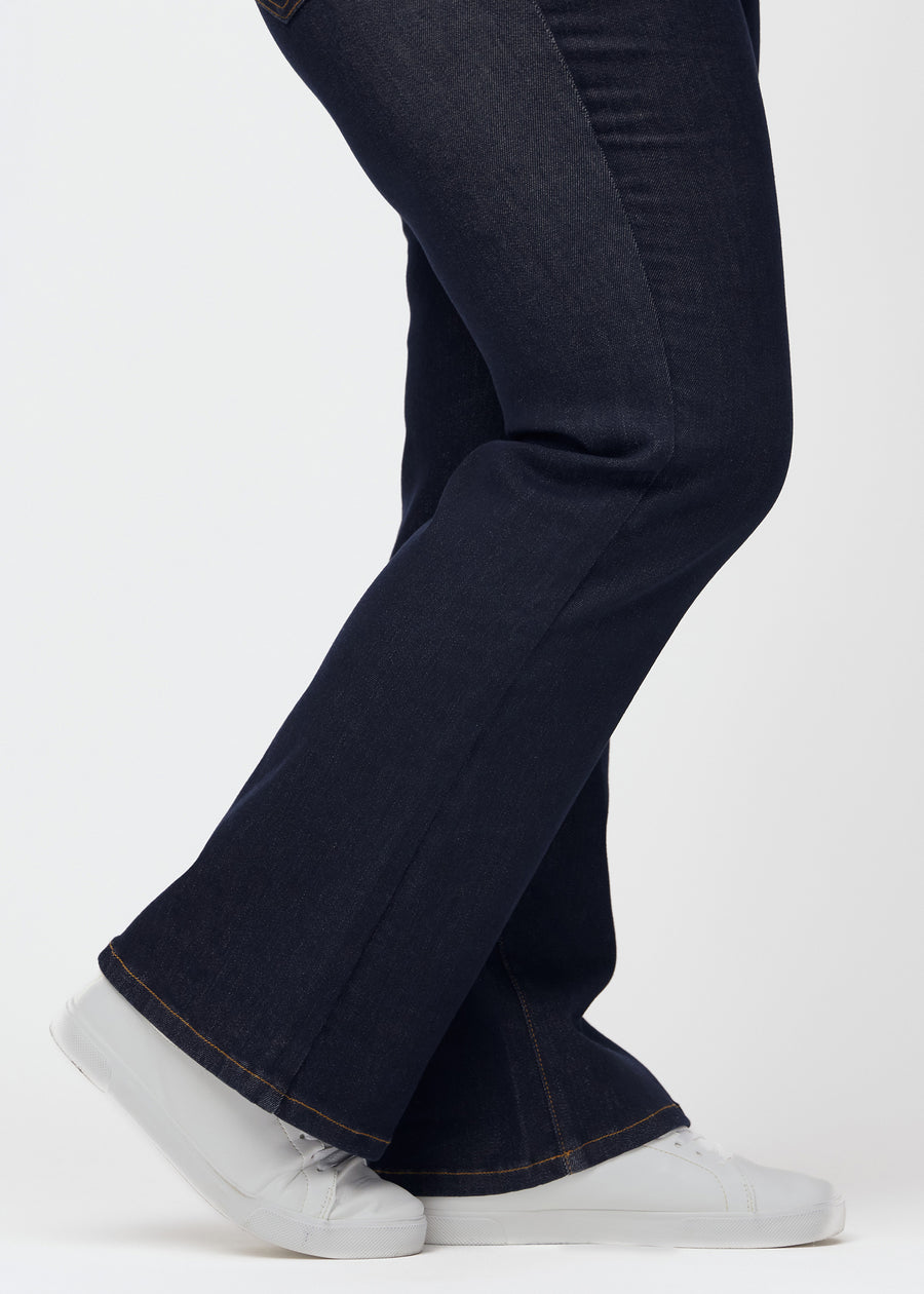 Dyp mørkeblå denim jeans til kvinner i fargen Midnights med bootcut-passform sett på nært hold ved anklene på plus-size-modell for å vise den lette slengen.