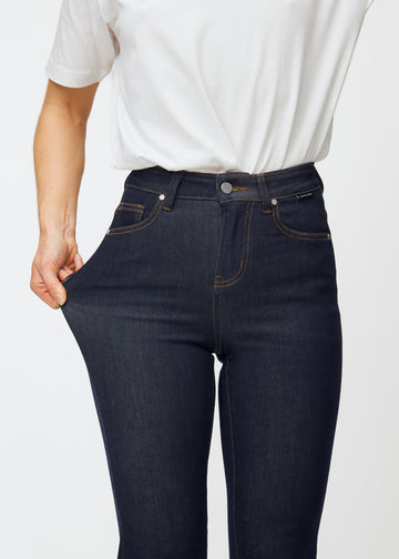Modellen strekker dyp mørkeblå denim jeans til kvinner i fargen Midnights ved låret for å vise materialets stretch.