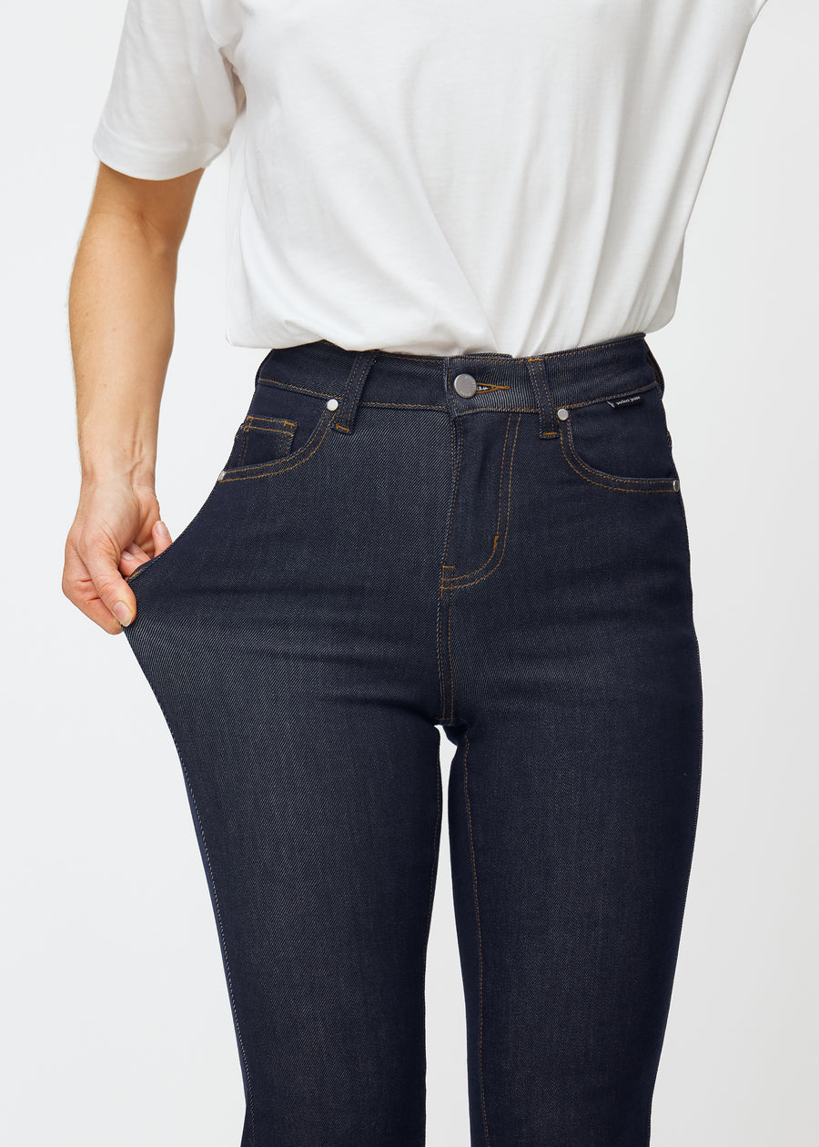 Modellen strekker dyp mørkeblå denim jeans til kvinner i fargen Midnights ved låret for å vise materialets stretch.