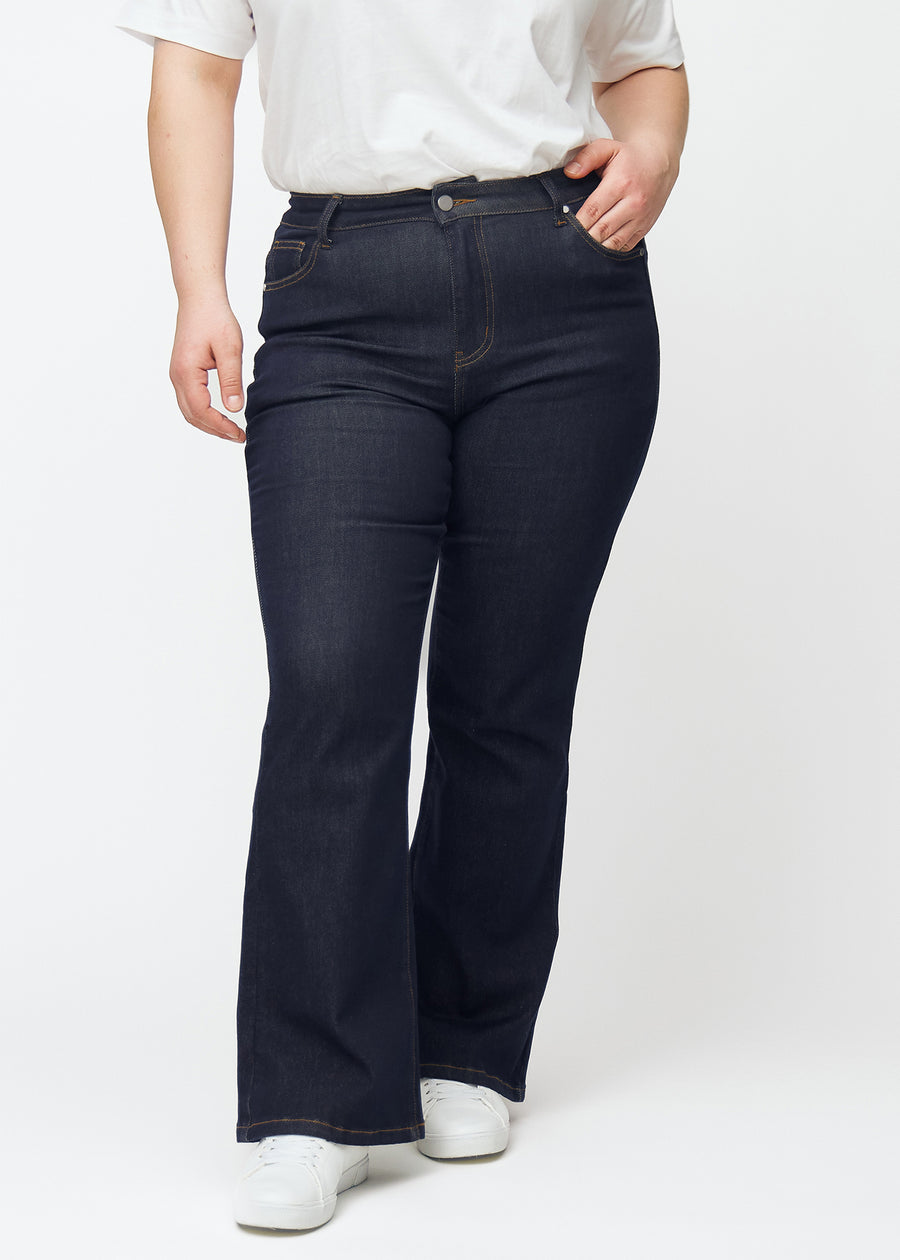 Dyp mørkeblå denim jeans til kvinner i fargen Midnights med bootcut-passform sett forfra på plus-size-modell.