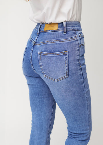 Blå mid-rise bootcut-jeans i fargen Rivers. Nærbilde bakfra på en modell for å vise detaljene.