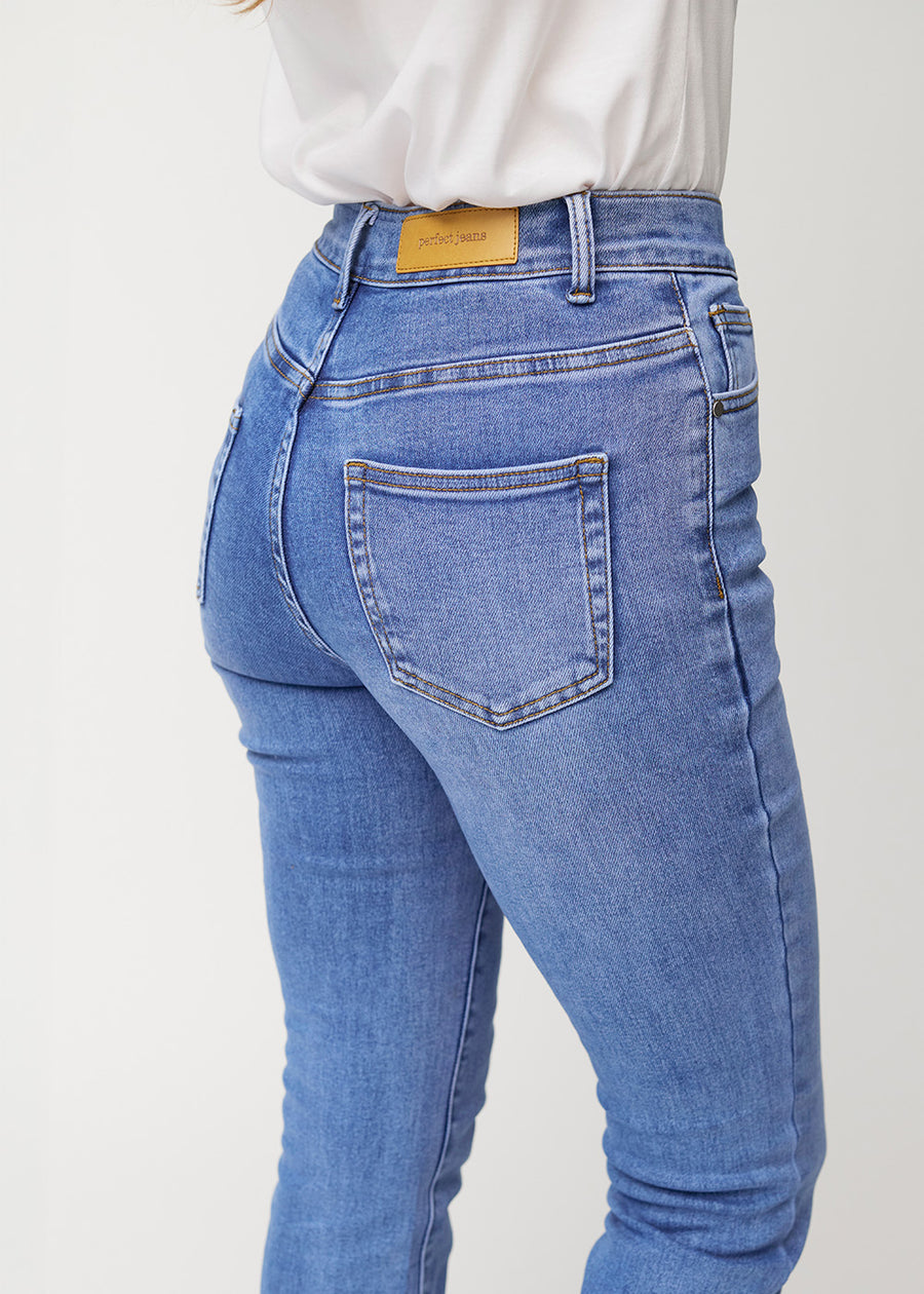 Blå mid-rise bootcut-jeans i fargen Rivers. Nærbilde bakfra på en modell for å vise detaljene.