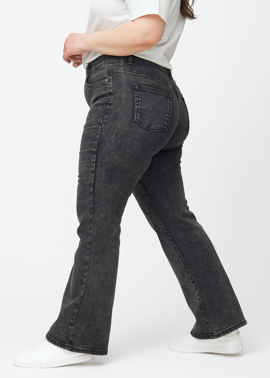 Mørkegrå mid-rise bootcut-jeans i fargen Shadows. Sett fra siden på en plus size-modell.