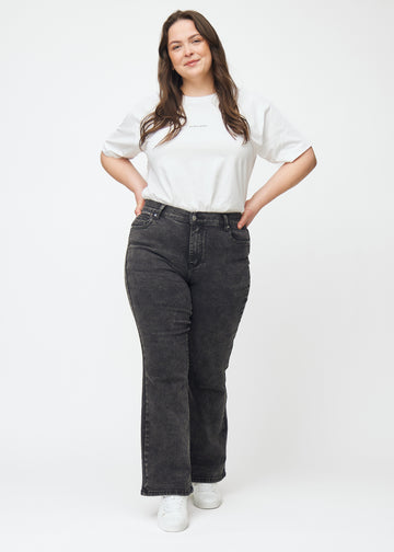 Mørkegrå mid-rise bootcut-jeans i fargen Shadows. Helhetsbilde av en plus size-modell med jeansene på.