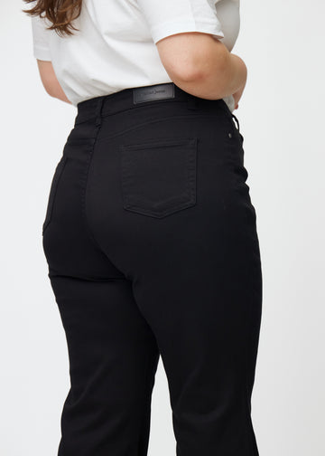 Svarte høytaljede bootcut jeans sett bakfra på nært hold på en plus-size-modell for å vise detaljer.