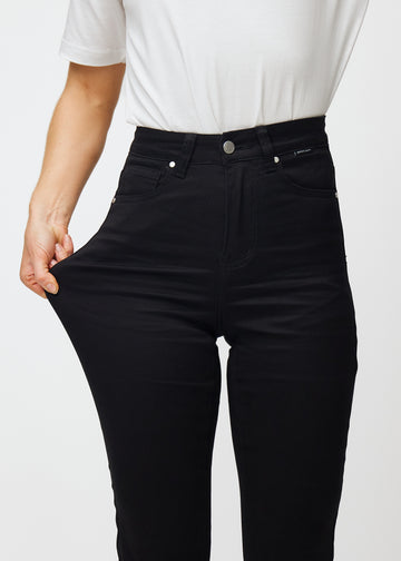 Modellen strekker jeansene ved låret for å vise stretch.
