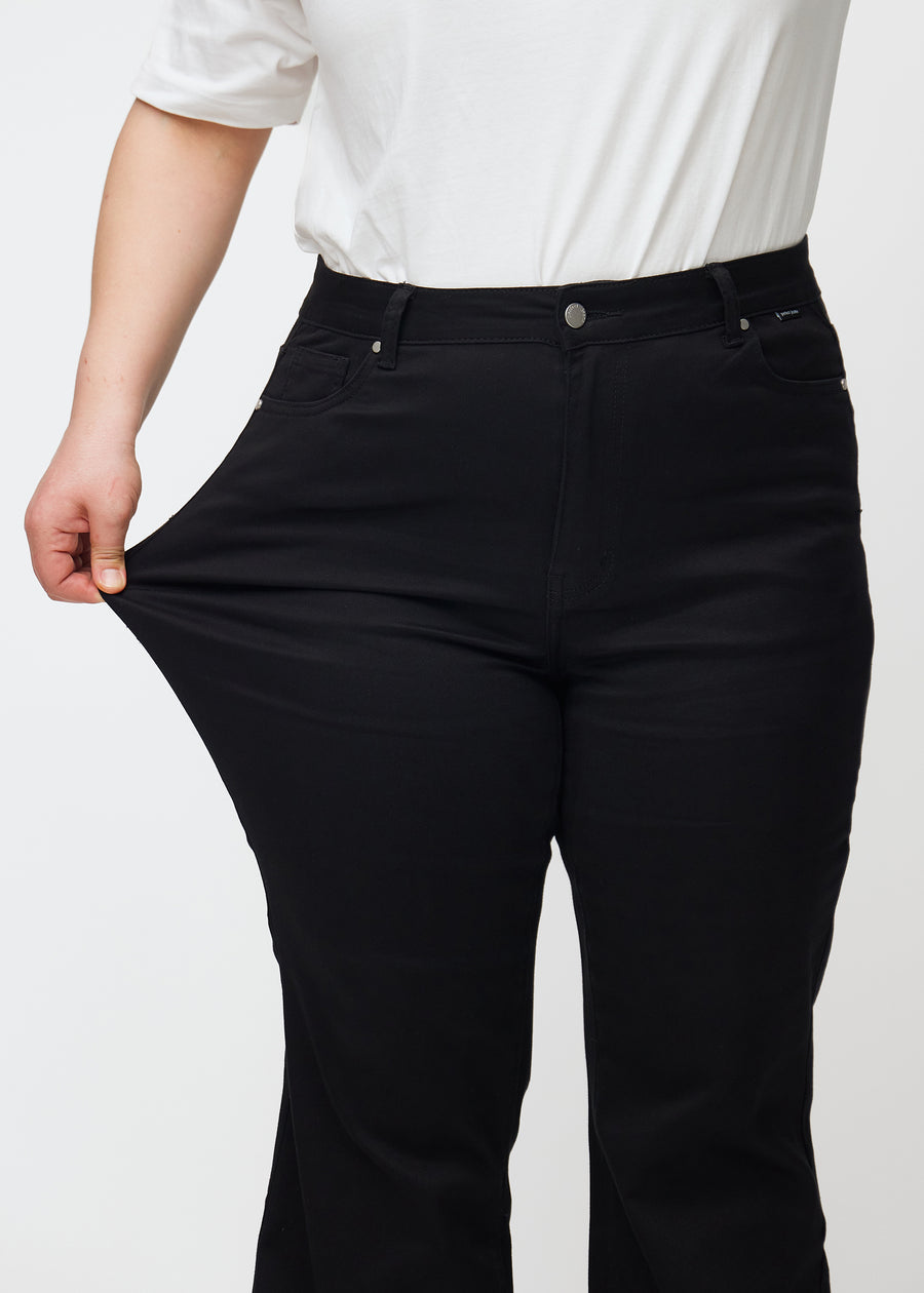 Plus-size-modellen strekker jeansene ved låret for å vise stretch.