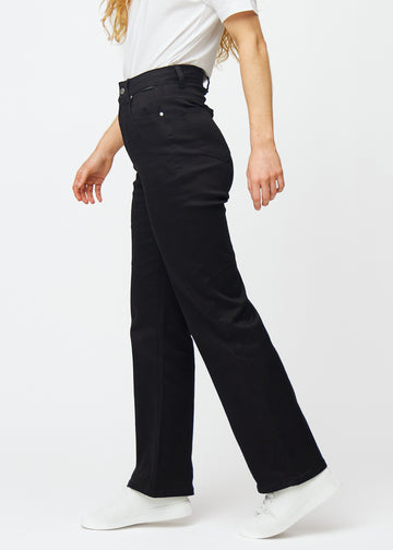 Svarte høytlivede jeans, som sitter til i midjen og har en løs passform med vidde nedover, sett fra siden på en modell.