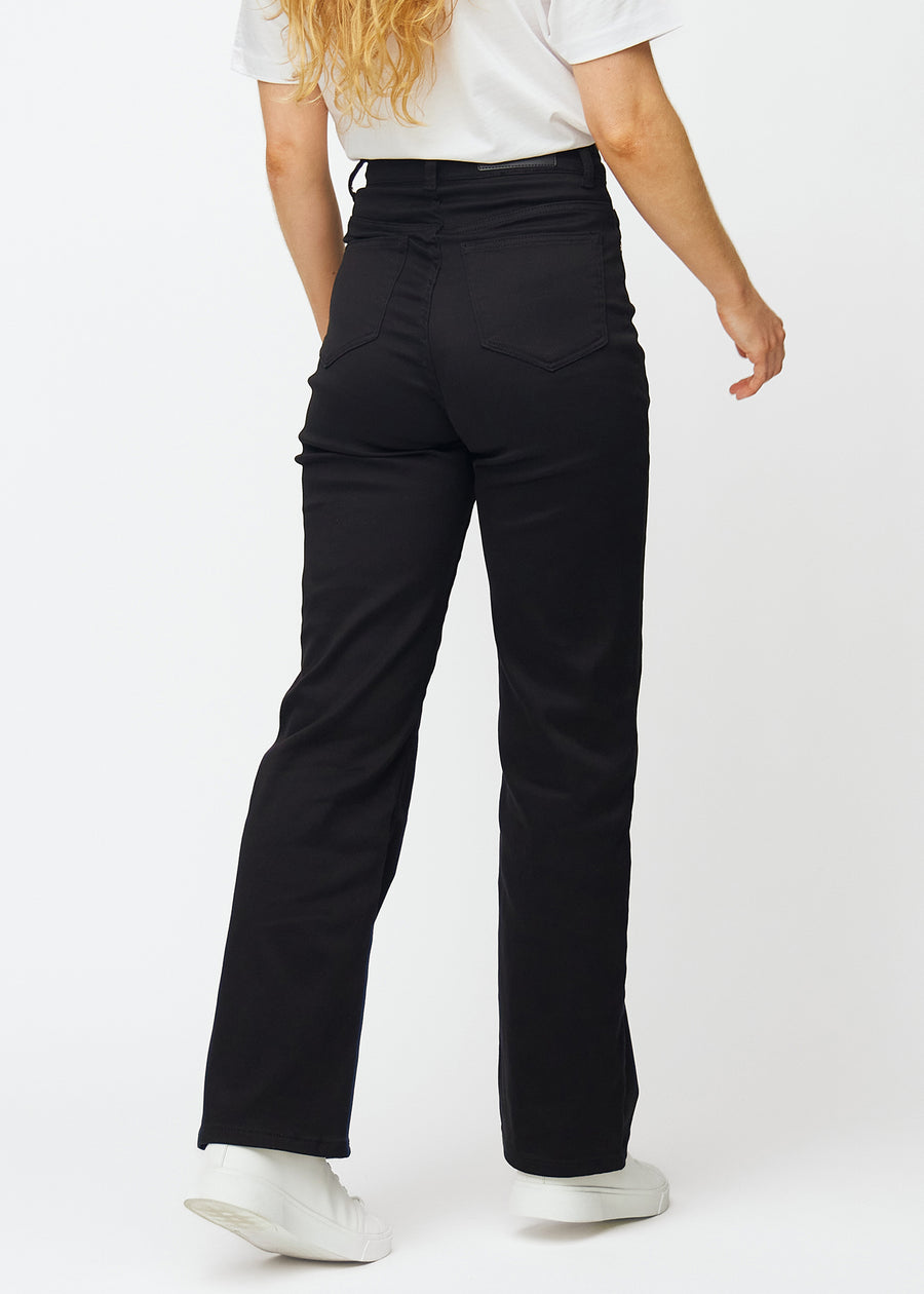 Svarte høytlivede jeans, som sitter til i midjen og har en løs passform med vidde nedover, sett bakfra for å vise hele produktet.