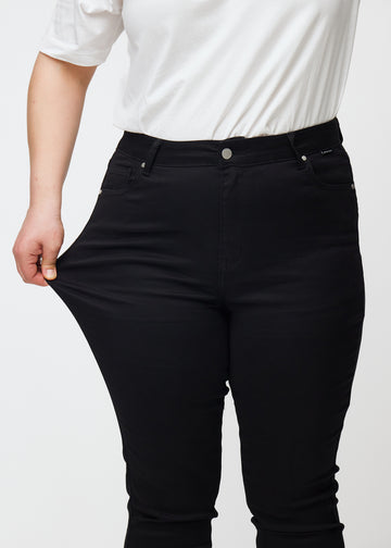 En plus size-modell strekker de svarte stretch jeans med høy midje i fargen Ravens.