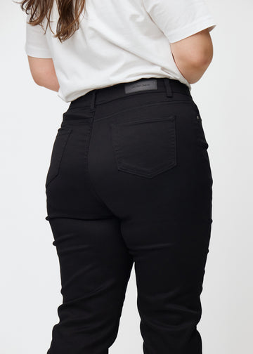Svarte høytaljede slim jeans sett bakfra på nært hold på en plus-size-modell for å vise detaljer.