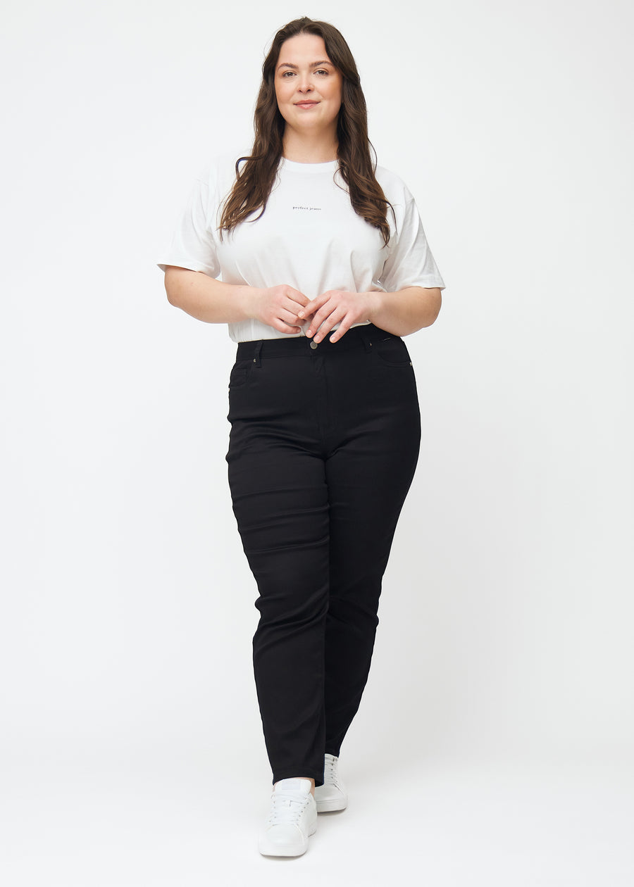 Fullt bilde av en plus-size-modell i svarte høytaljede slim jeans.