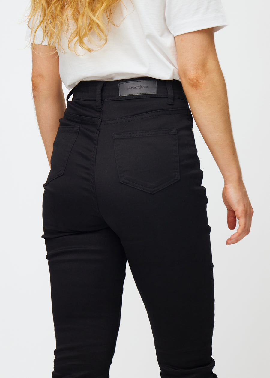 Svarte høytaljede slim jeans sett bakfra på nært hold for å vise detaljer.