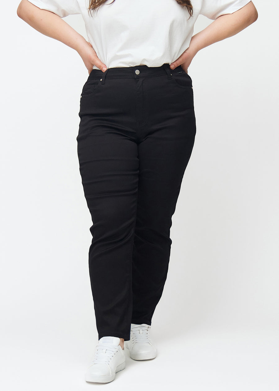 Svarte høytaljede slim jeans, modellnavn Ravens, som sitter tett til benet, men litt løsere ved ankelen, på en plus-size-modell, sett forfra.