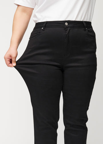 Plus-size-modellen strekker jeansene ved låret for å vise stretch.