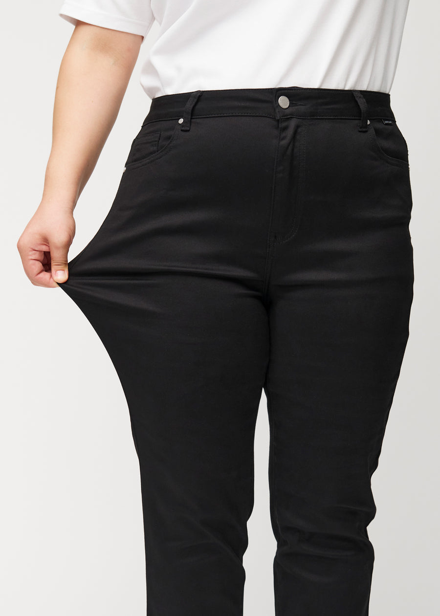 Plus-size-modellen strekker jeansene ved låret for å vise stretch.