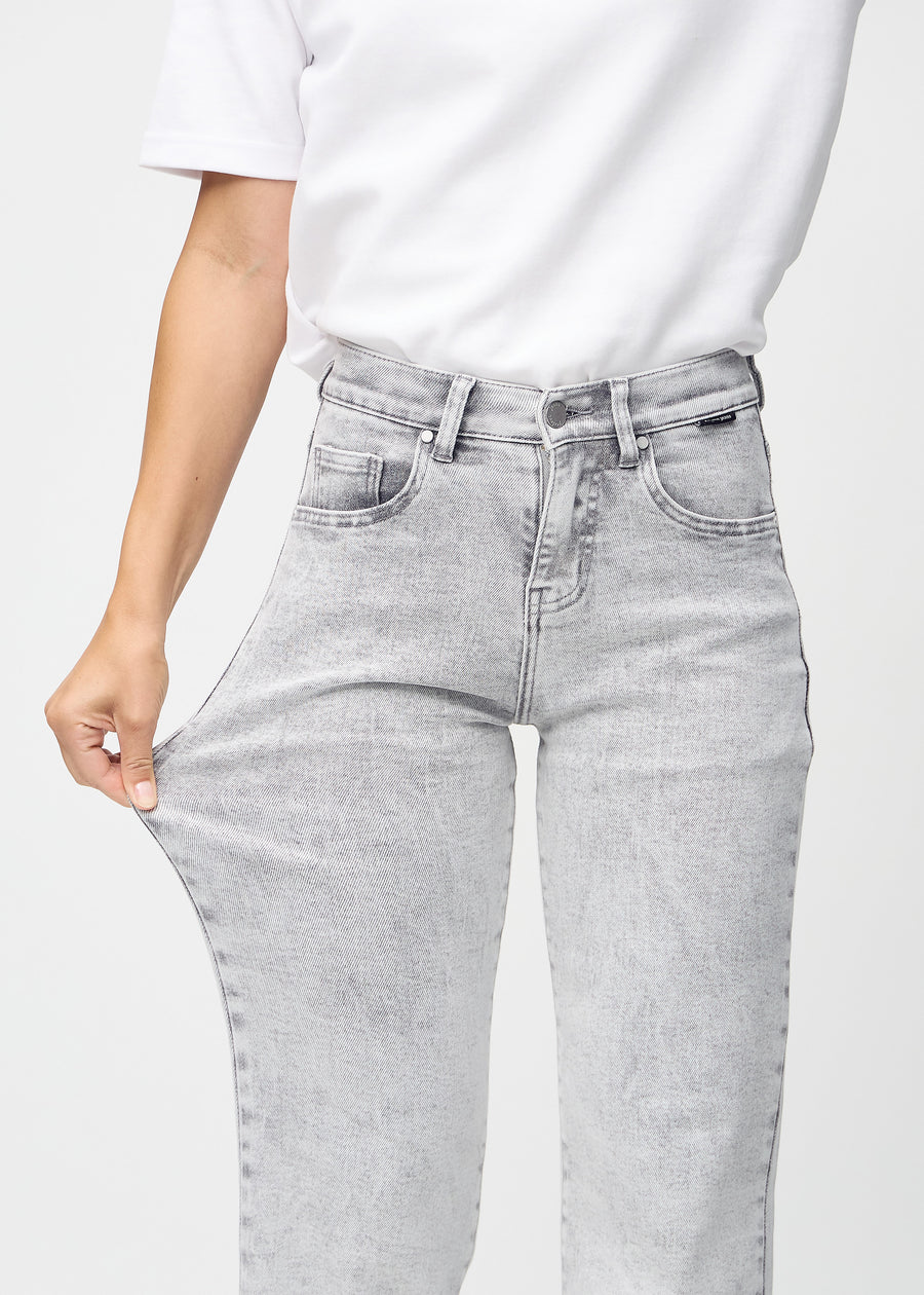 Loose-jeans til kvinner i lysegrå, fargen Ashes. En modell strekker jeansstoffet ved låret for å vise stretchen.