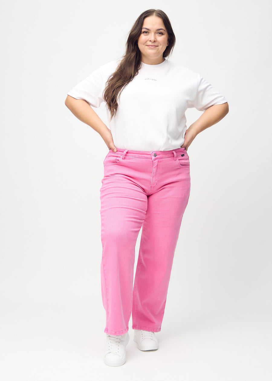 Loose-jeans til kvinner i lyserosa, fargen Flamingos. Helhetsbilde av en plus size-modell med løstsittende jeans.
