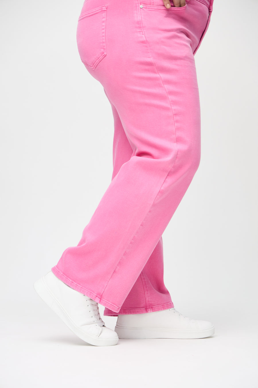 Loose-jeans til kvinner i lyserosa, fargen Flamingos. Nærbilde ved anklene på en plus size-modell, som viser de vide benavslutningene.