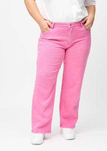 Loose-jeans til kvinner i lyserosa, fargen Flamingos. Sett forfra på en plus size-modell, med romslig passform og vide ben.
