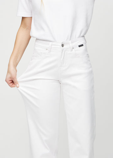 Loose-jeans til kvinner i hvit, fargen Marguerites. En modell strekker jeansstoffet ved låret for å vise stretchen.