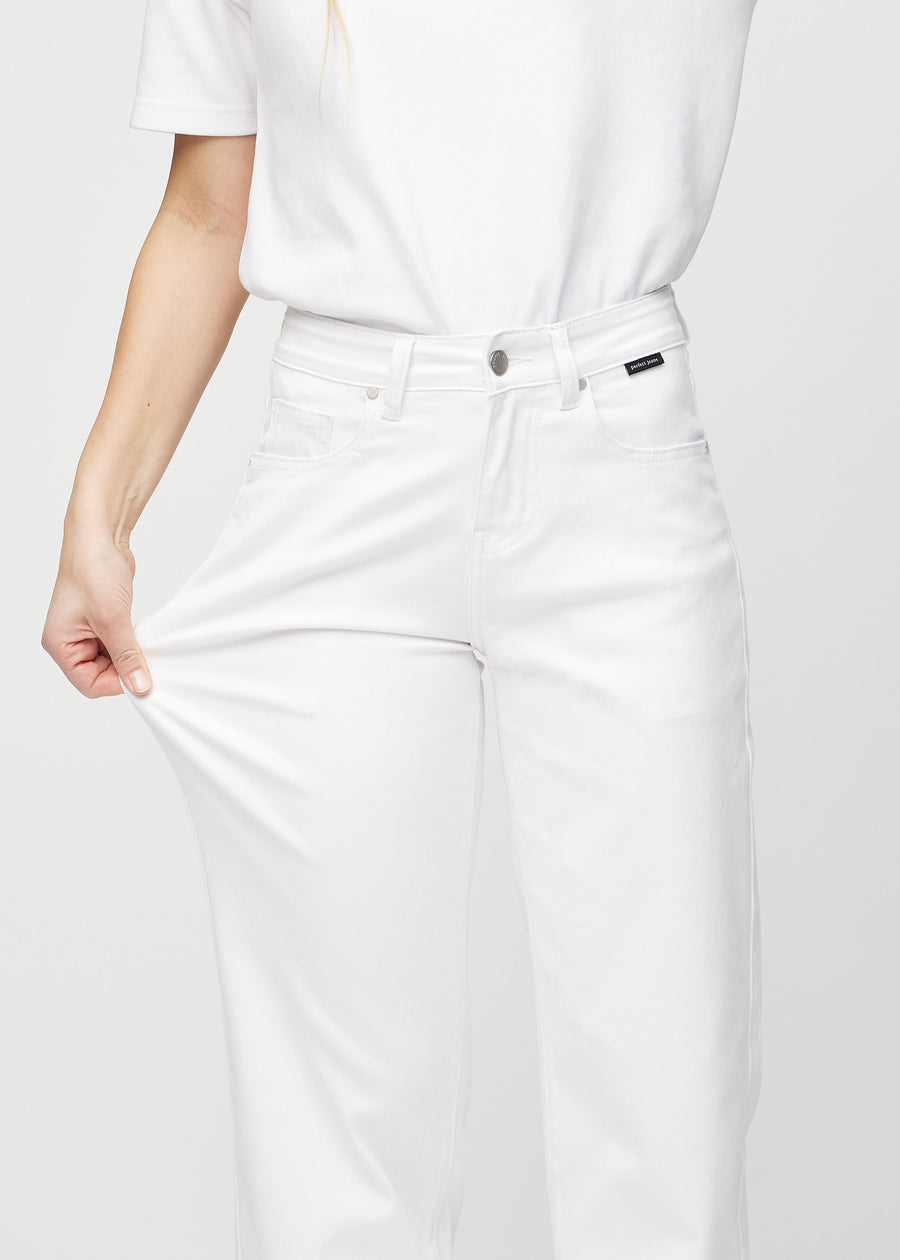 Loose-jeans til kvinner i hvit, fargen Marguerites. En modell strekker jeansstoffet ved låret for å vise stretchen.
