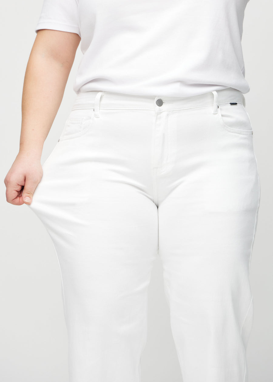 Loose-jeans til kvinner i hvit, fargen Marguerites. En plus size-modell strekker jeansstoffet ved låret for å vise stretchen.