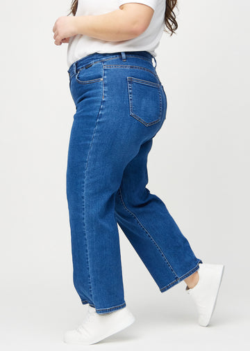 Loose-jeans til kvinner i mørkeblå, fargen Oceans. Sett fra siden på en plus size-modell, med synlig løs passform.