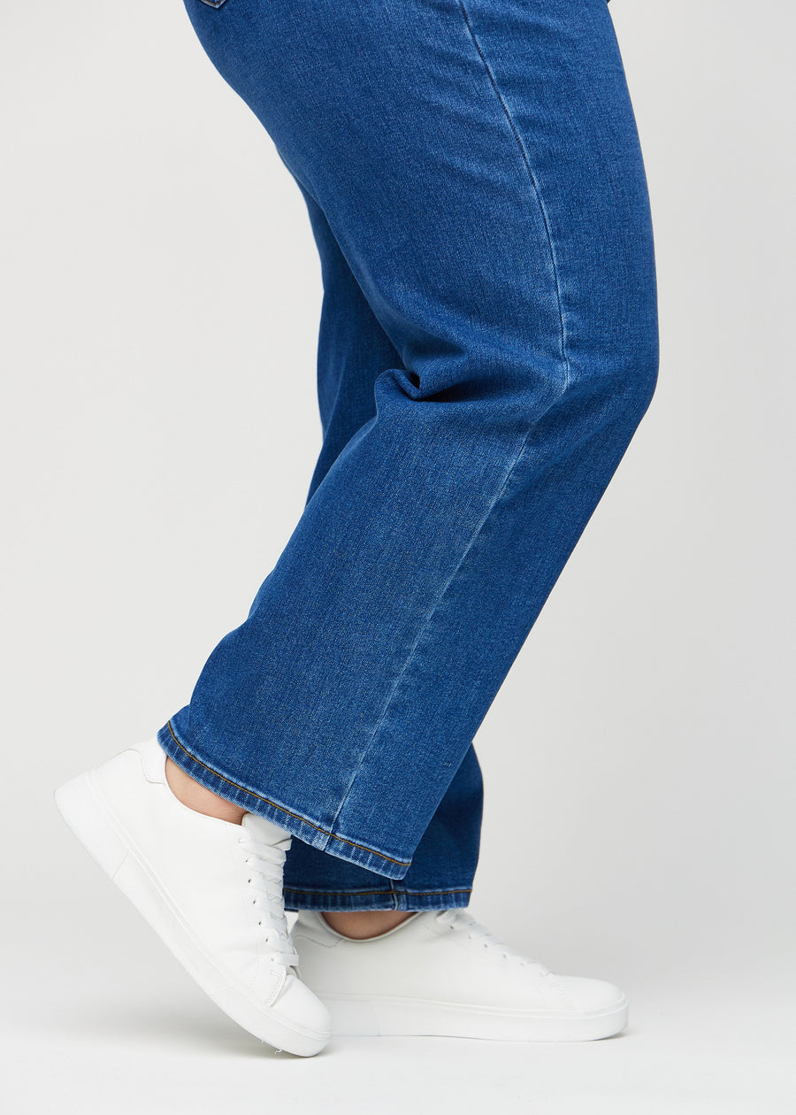 Loose-jeans til kvinner i mørkeblå, fargen Oceans. Nærbilde ved anklene på en plus size-modell, som viser de vide benavslutningene.