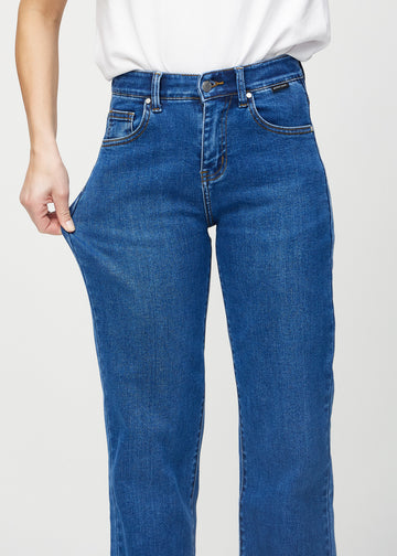 Loose-jeans til kvinner i mørkeblå, fargen Oceans. En modell strekker jeansstoffet ved låret for å vise stretchen.