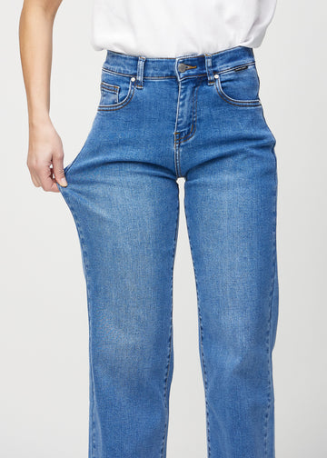 Loose-jeans til kvinner i blå, fargen Rivers. En modell strekker jeansstoffet ved låret for å vise stretchen.