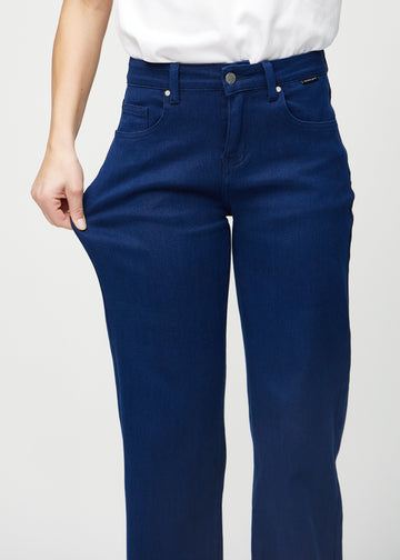 Loose-jeans til kvinner i mørkeblå, fargen Royals. En modell strekker jeansstoffet ved låret for å vise stretchen.