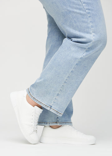 Loose-jeans til kvinner i lyseblå, fargen Waves. Nærbilde ved anklene på en plus size-modell, som viser de vide benavslutningene.