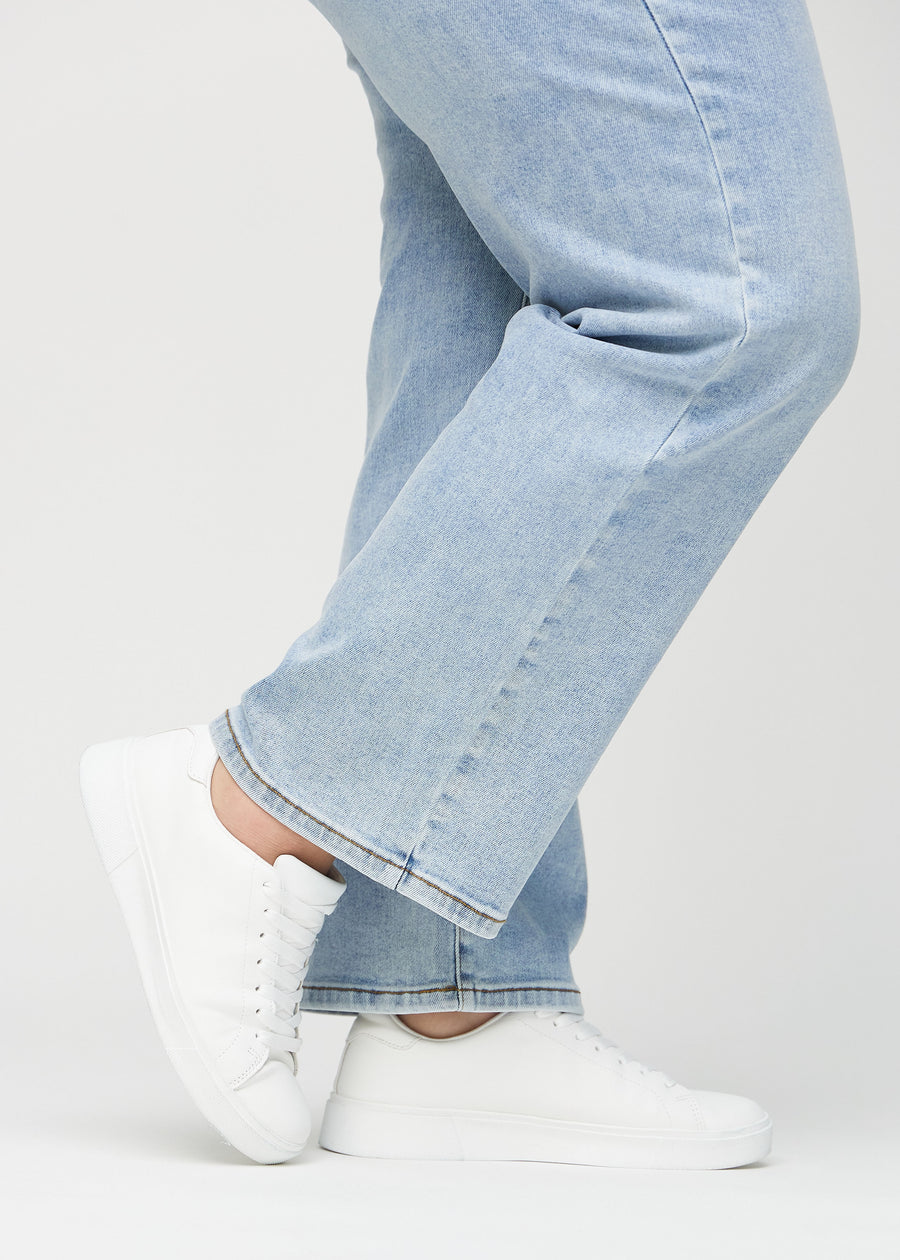 Loose-jeans til kvinner i lyseblå, fargen Waves. Nærbilde ved anklene på en plus size-modell, som viser de vide benavslutningene.