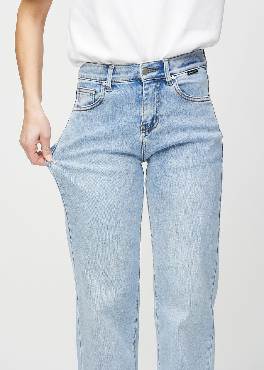 Loose-jeans til kvinner i lyseblå, fargen Waves. En modell strekker jeansstoffet ved låret for å vise stretchen.